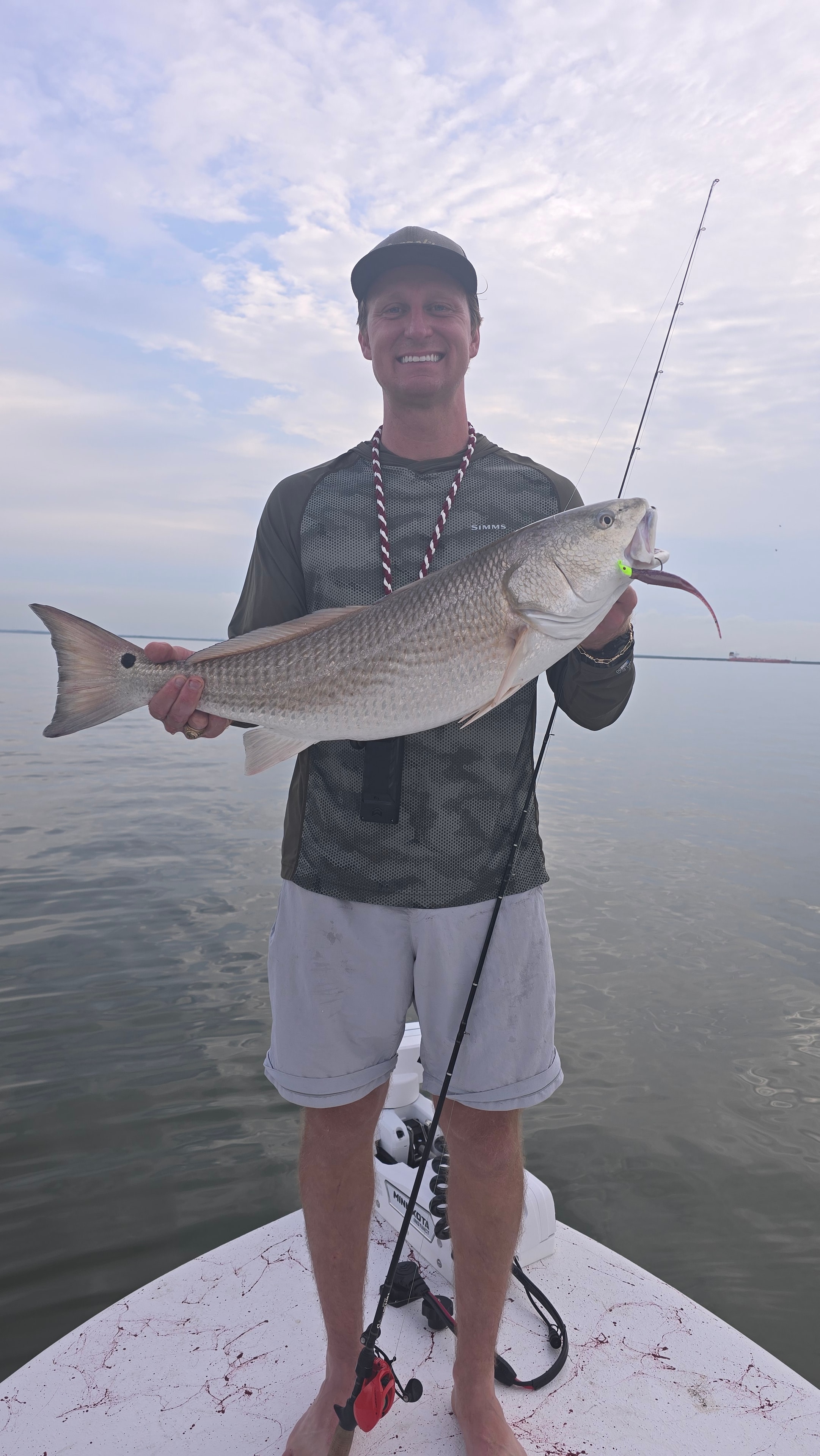Fisherman holding a redfish from the bow of a boat
