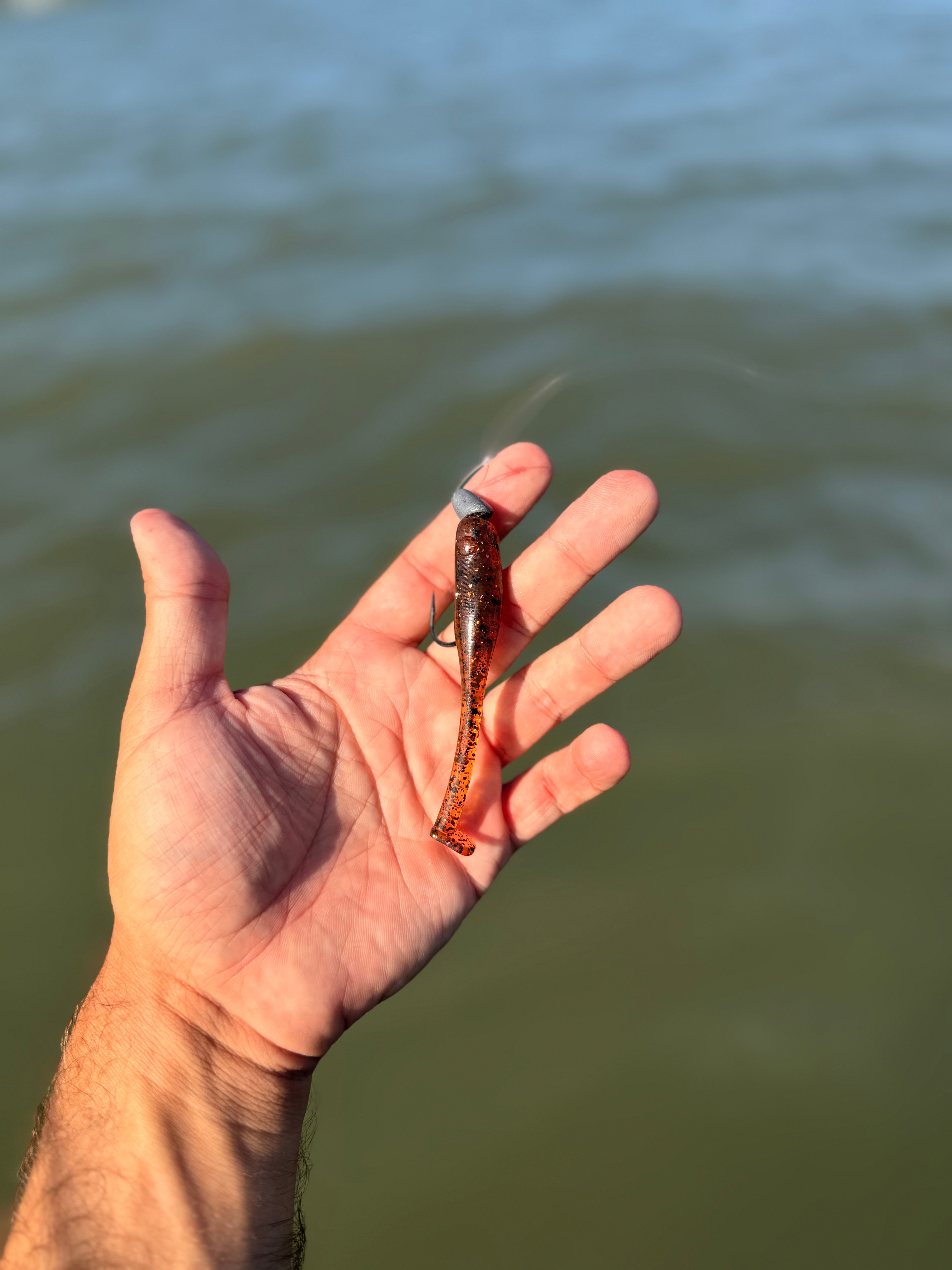KTX Baits soft-plastic lure held over coastal water